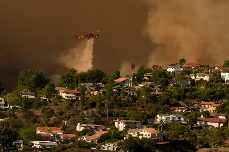 A plane drops water over the Palisades Fire