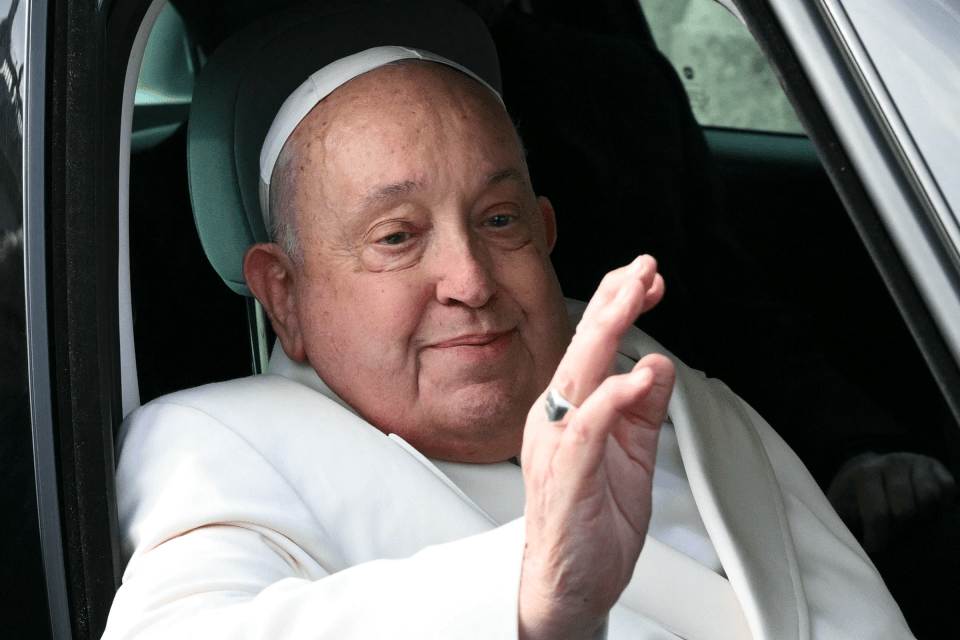 Pope Francis waving from a car.